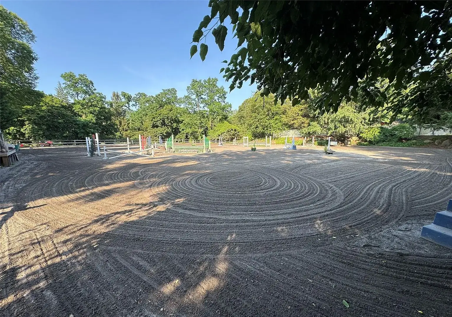 Freshly dragged arena footing with the jump course beyond