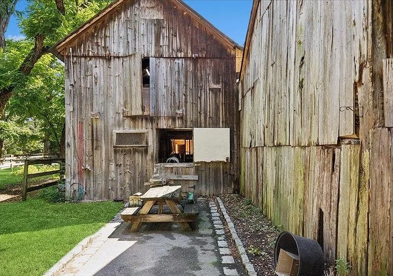 The original weathered barn buildings and picnic table on the property