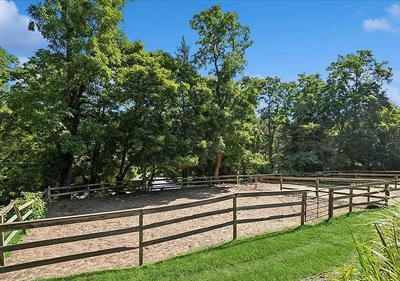 Board-fenced grass paddock bordered by woods