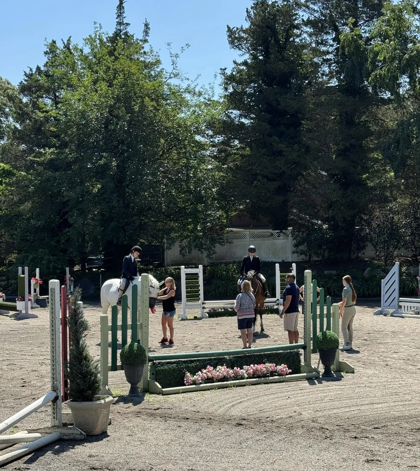 Two Winding Hill riders schooling over a flower box in the warm-up ring at a horse show